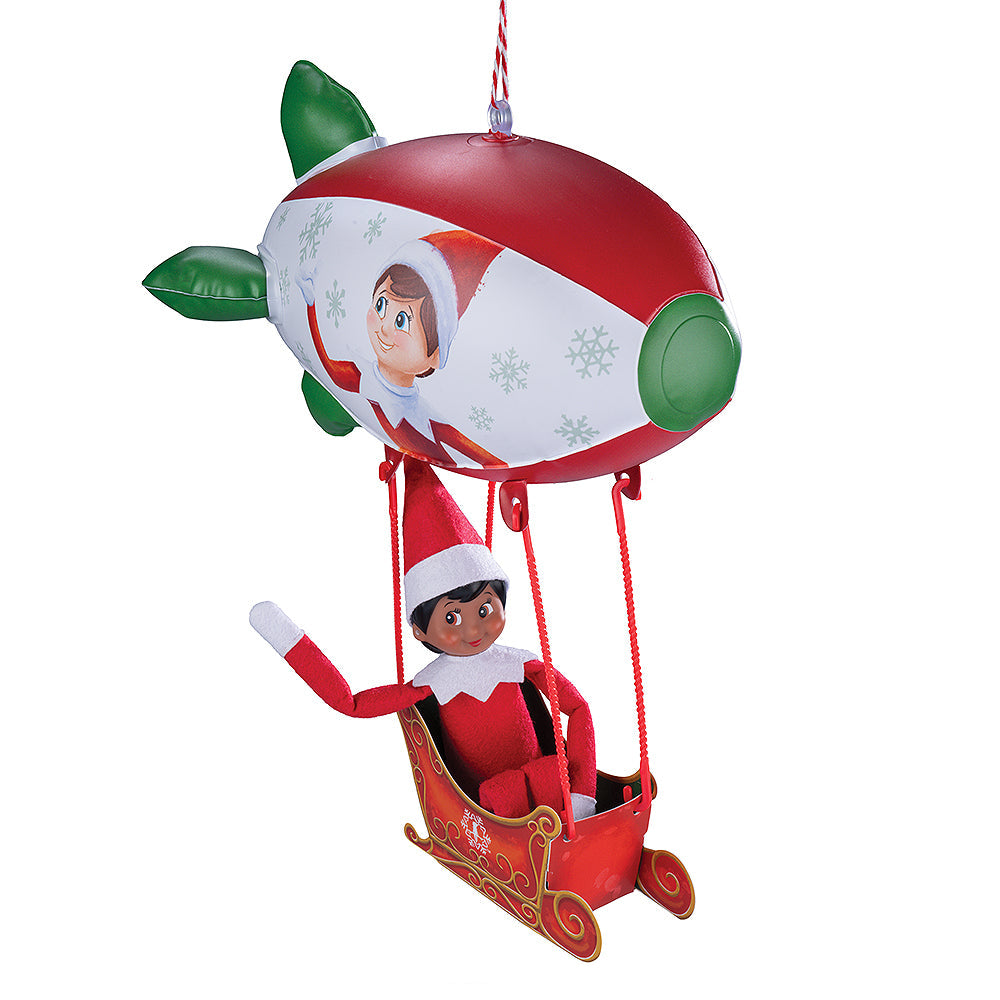 A girl Scout Elf® takes a ride in the Polar Props™ Peppermint Blimp, waving to those passing by.