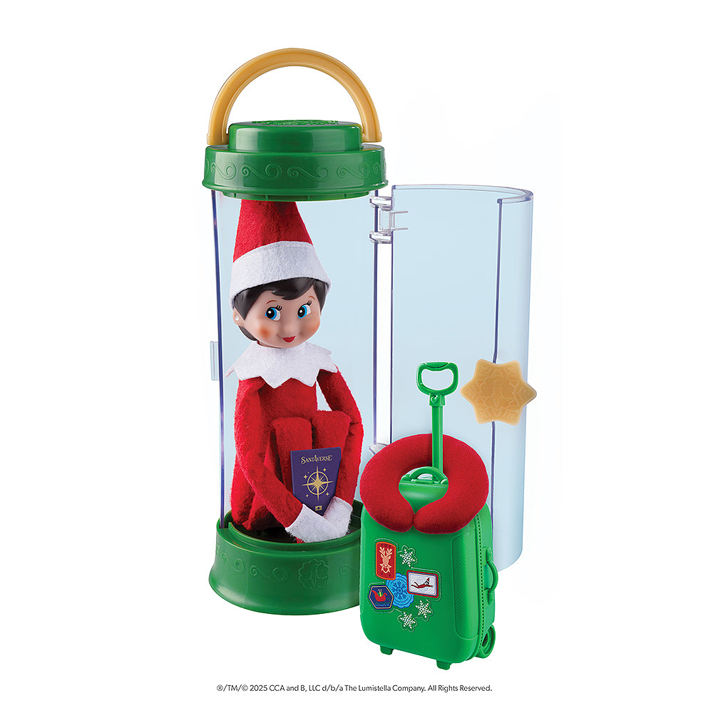 A girl Scout Elf® sitting in the Scout Elf® Carrier, Ltd. 20th Anniversary Ed. Kit with passport in hand. Also in tow is her luggage and neck pillow.