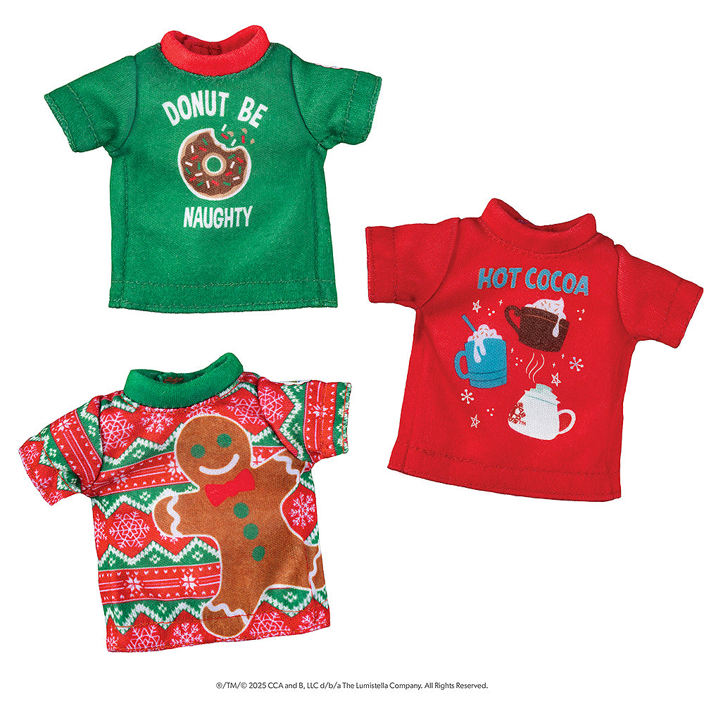 A flat lay view of the Claus Couture Collection® Festive Fun T-Shirt Set: a green tee with red collar with a donut graphic and the words, "Donut Be Naughty", a red tee with hot cocoa graphics and the words, "Hot Cocoa", and a green and red Fair Isle pattern with snowflakes and a large gingerbread man graphic.