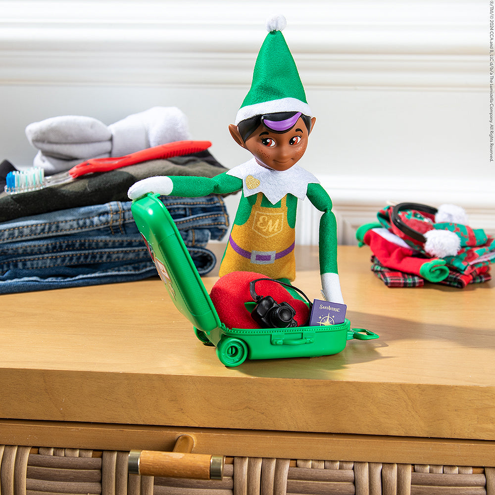 Elf Mates® Toy Maker packing his suitcase using the Polar Props™ Travel Set in preparation for a trip with his family
