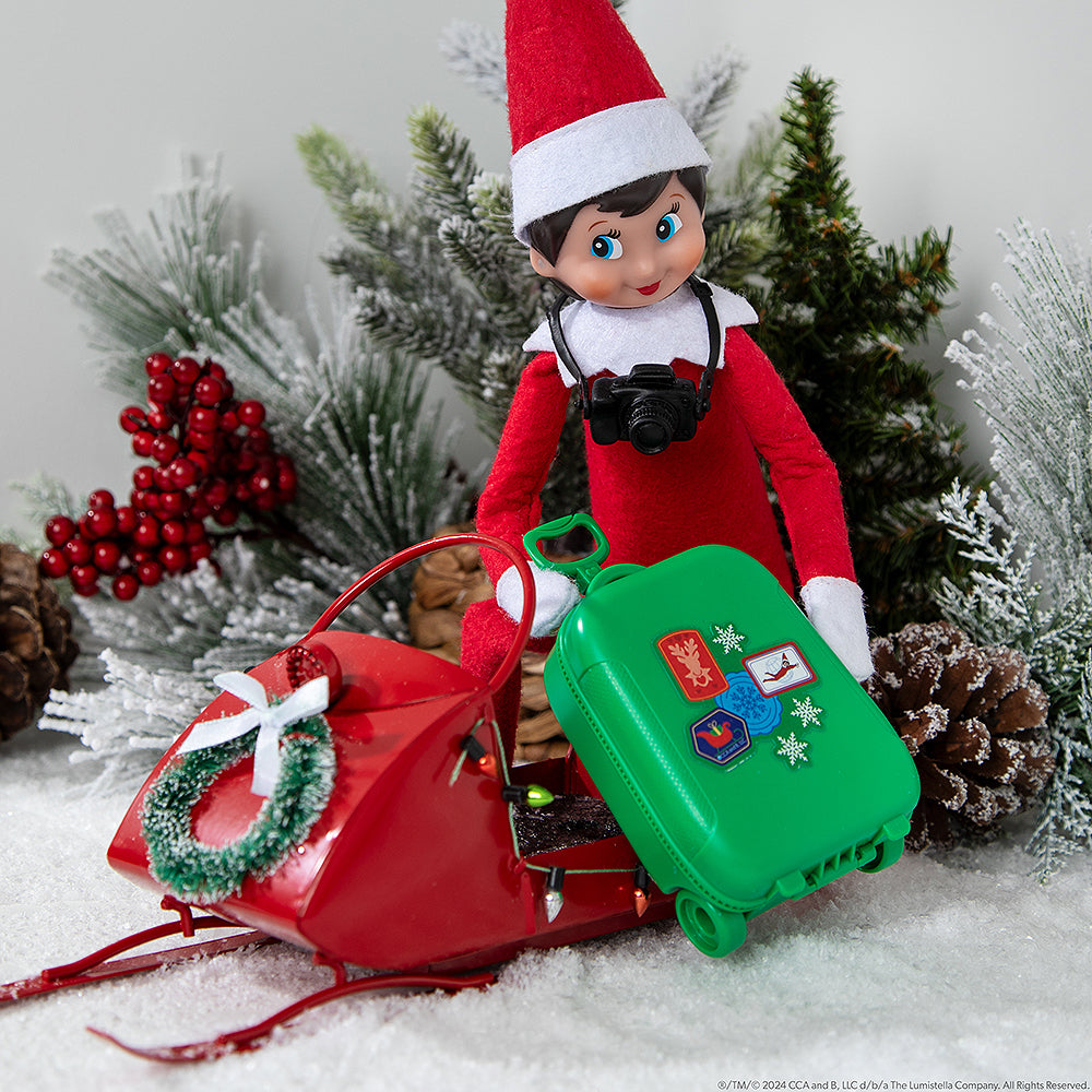 Scout Elf® with Polar Props™ Travel Set suitcase loaded up on a Christmasy snowmobile
