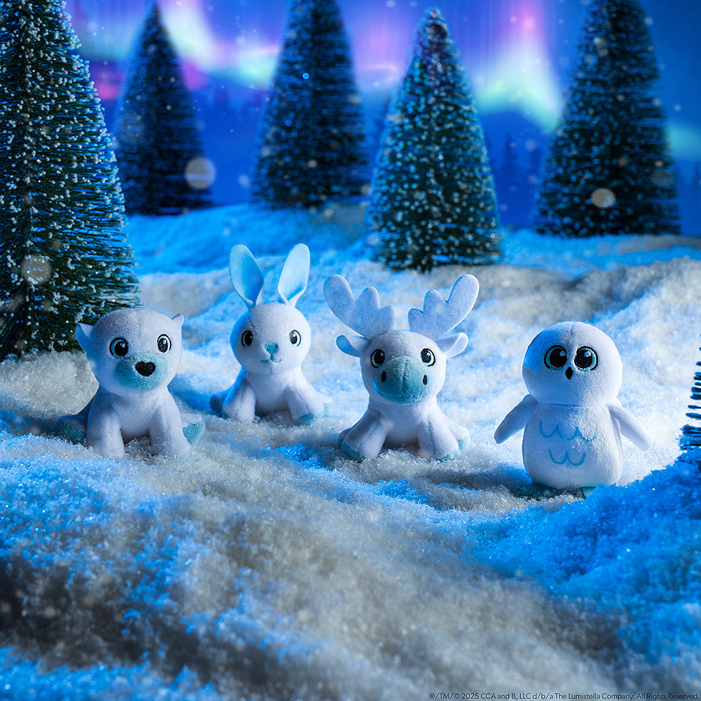 This image features the 4 mini plush snow sculpture designs that you could get in the Noorah™ Snow Sculpture Surprise. They are posing in an arctic environment with snowy conifer trees and the Northern Lights overhead.