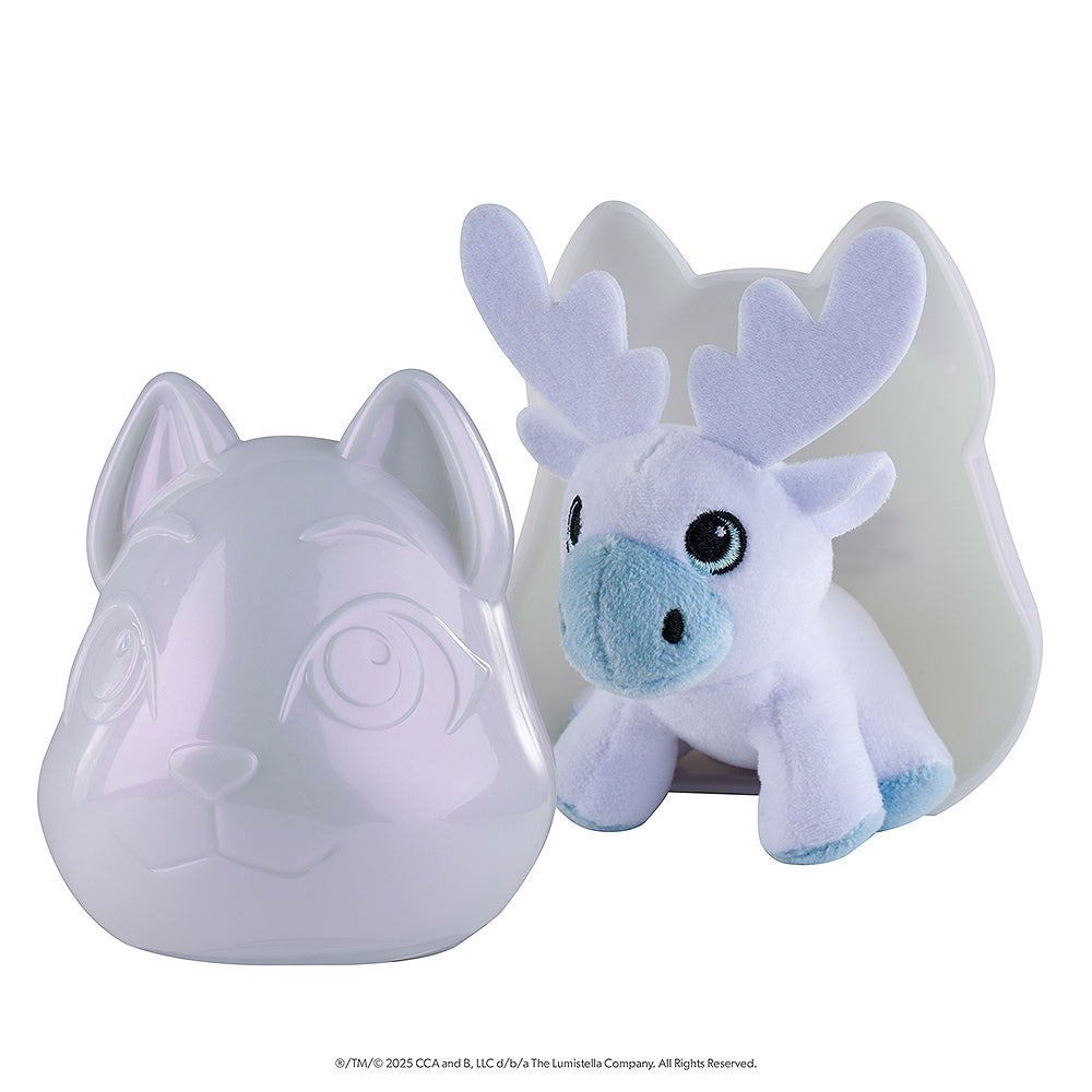 A tilted side-view of the front of packaging of the Noorah™ Snow Sculpture Surprise, which features Noorah's head as a plastic surprise container, pictured open with the cute reindeer character in white and light blue positioned inside the back piece of the container.