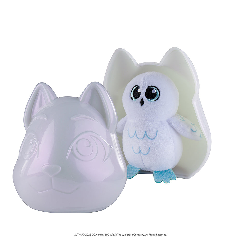 A tilted side-view of the front of packaging of the Noorah™ Snow Sculpture Surprise, which features Noorah's head as a plastic surprise container, pictured open with the cute owl character in white and light blue positioned inside the back piece of the container.