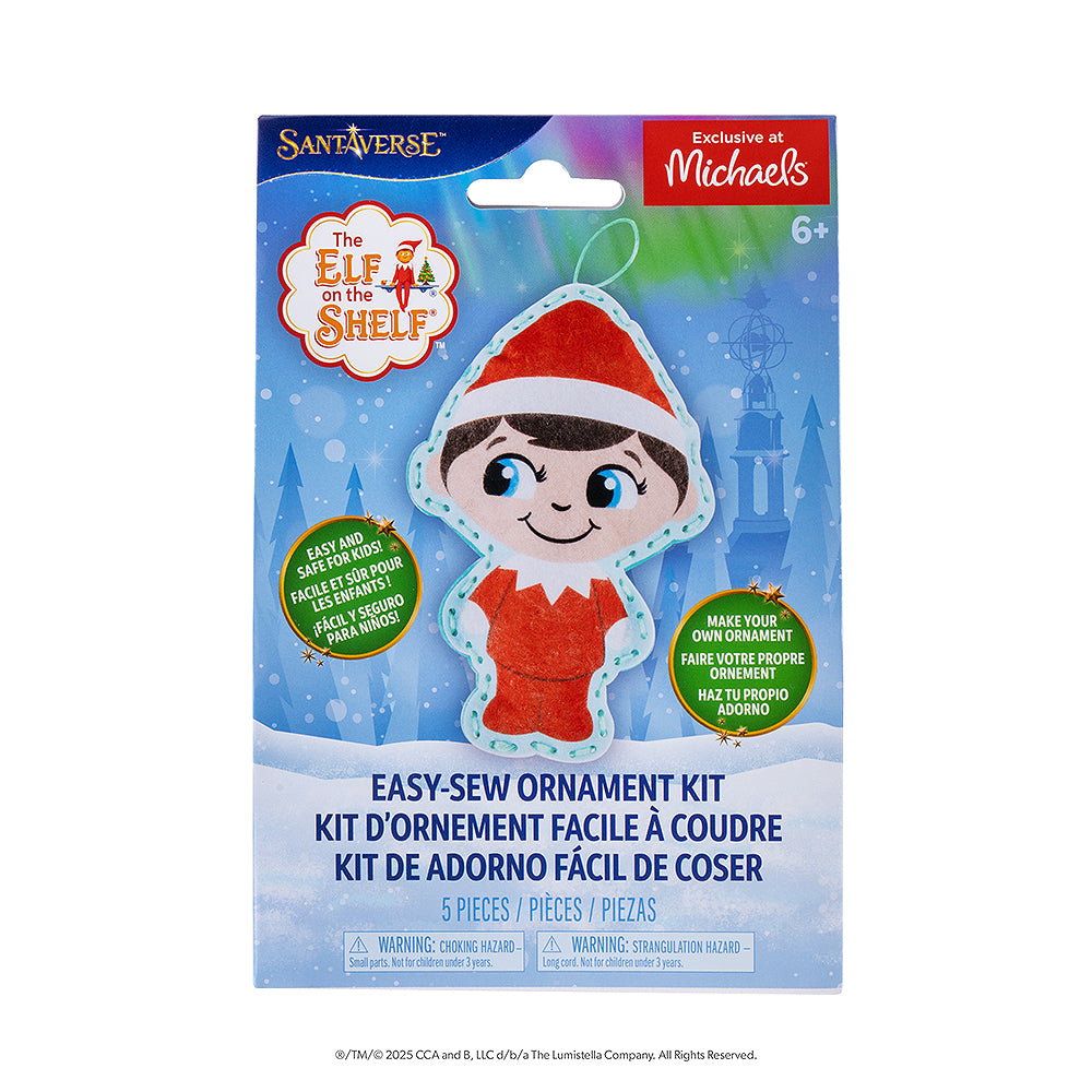 A front view of the packaging of The Elf on the Shelf® Easy-Sew Ornament Kit. The packaging has the finished product, The Elf on the Shelf and Santaverse logos and other details. The packaging also has an "Exclusive at Michaels" label on it in the top right-hand corner. The background is a vector background commonly associated with the Santaverse brand, featuring conifer trees, light bursts, snowflakes, the Northern Lights, and a snow-covered landscape.