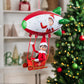 A boy Scout Elf® takes a ride and waves from the Polar Props™ Peppermint Blimp, with a Christmas tree and decor blurred in the background of this lifestyle image.
