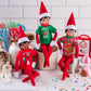A trio of Scout Elves, each sporting a t-shirt from the Claus Couture Collection® Festive Fun T-Shirt Set, staged on a kitchen countertop surrounded by sweet, festive treats.