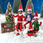 3 Scout Elves® posing in the snow with a strand of Christmas lights and ornaments while donning their tees from the Claus Couture Collection® Christmas T-Shirt Party Pack