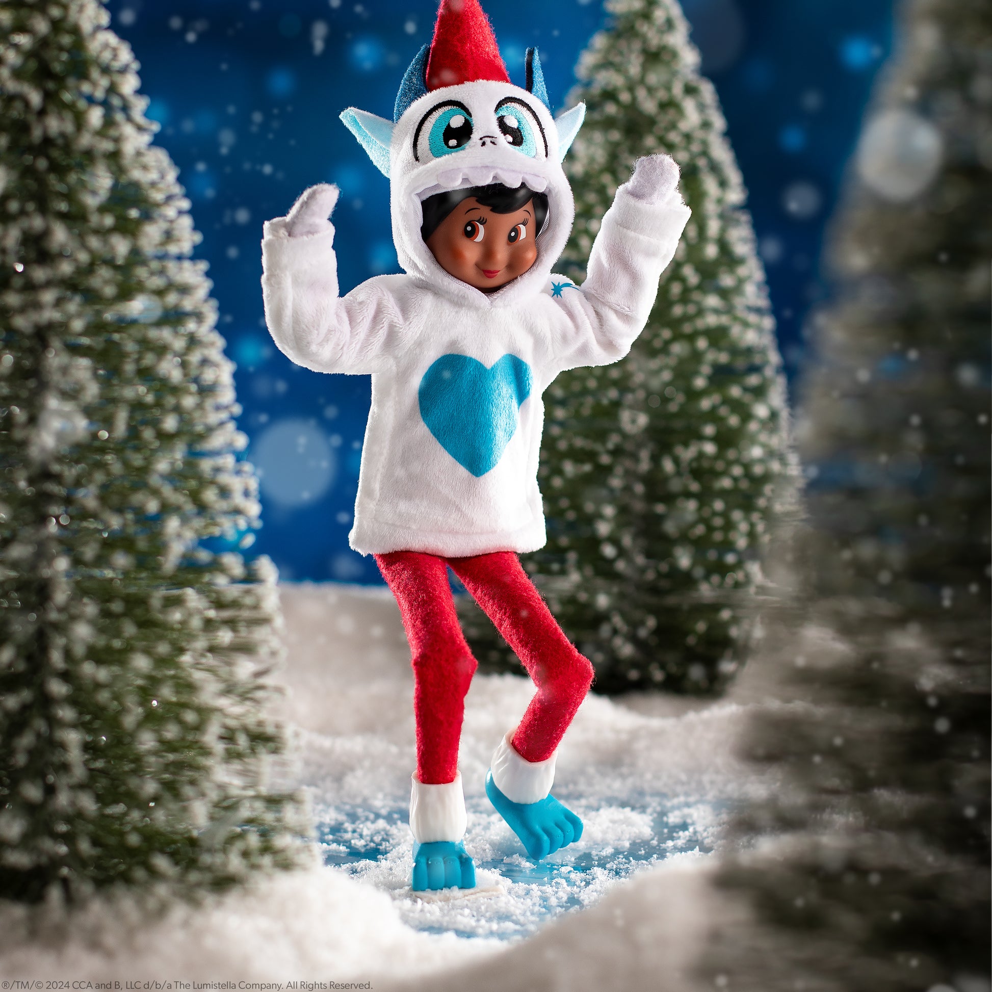 A girl Scout Elf® playfully creeps around a snowy forest while wearing the Claus Couture Collection® Yeti Hoodie Set