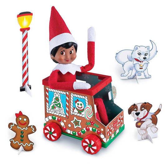 A Scout Elf® sitting in the DIY Gingerbread Truck flanked by the props included in the set