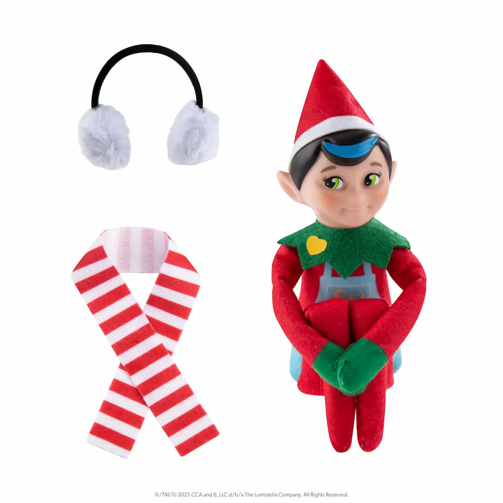 The Elf Mates® Chef with brown hair, posed sitting holding his knees to his chest. To the left of the elf is a set of earmuffs and a scarf.