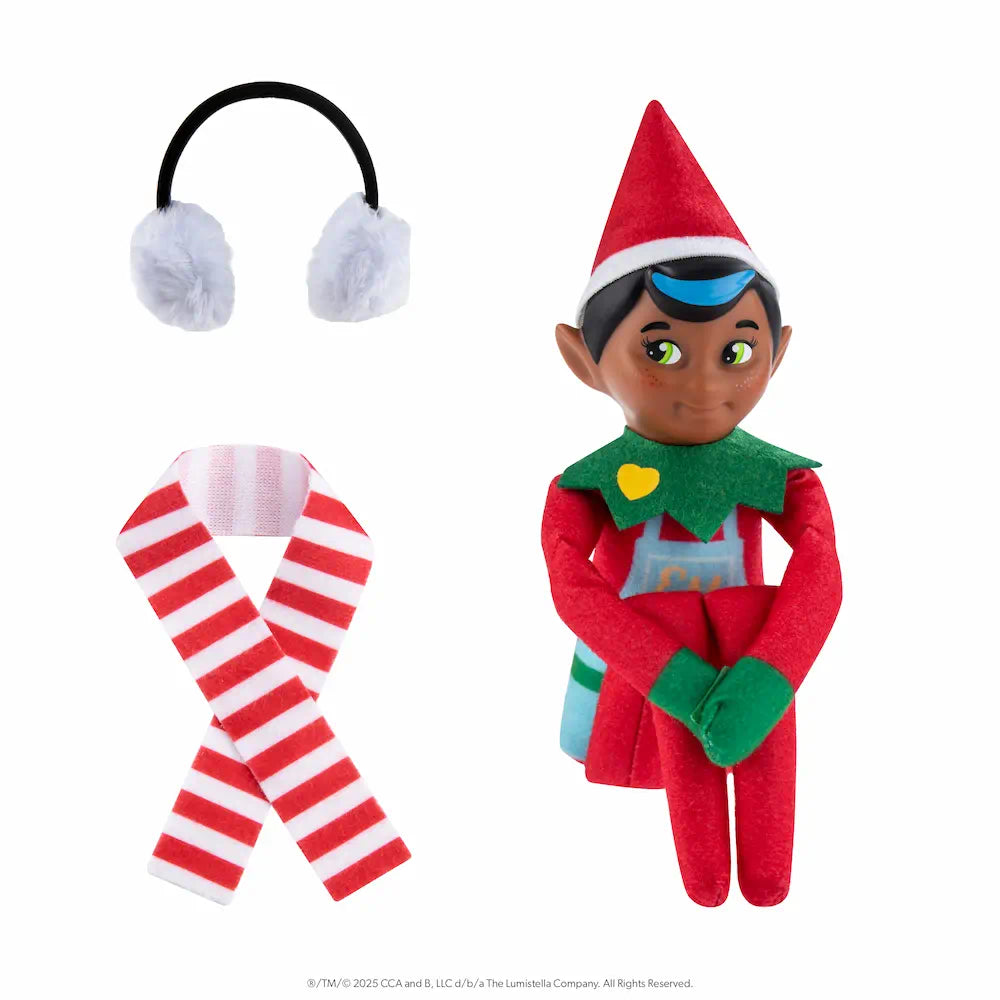 The Elf Mates® Chef with black hair, posed sitting holding his knees to his chest. To the left of the elf is a set of earmuffs and a scarf.
