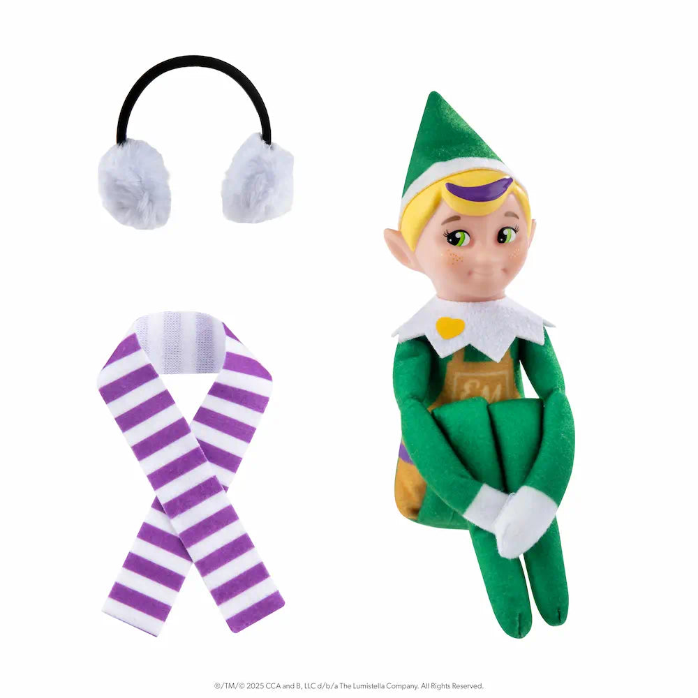 The Elf Mates® Toy Maker with blonde hair, posed sitting holding his knees to his chest. To the left of the elf is a set of earmuffs and a scarf.