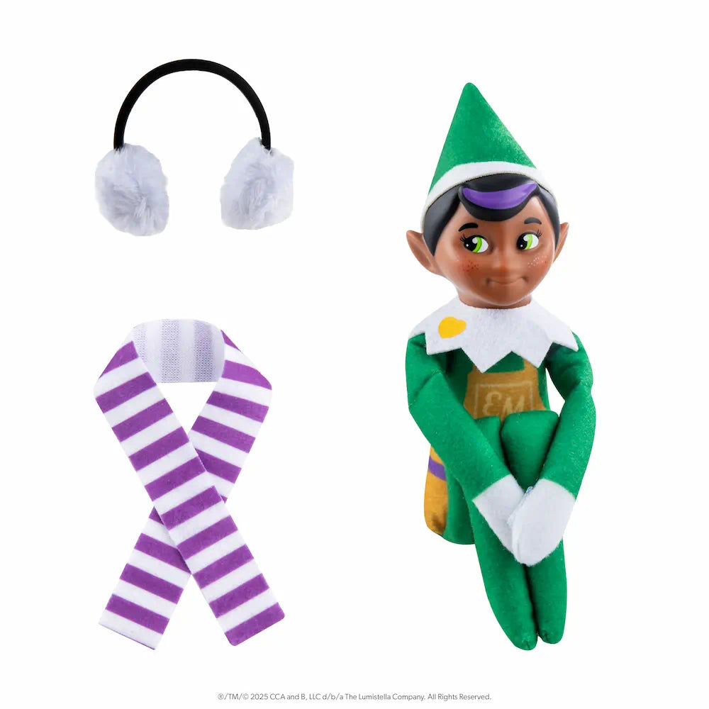 The Elf Mates® Toy Maker with black hair, posed sitting holding his knees to his chest. To the left of the elf is a set of earmuffs and a scarf.