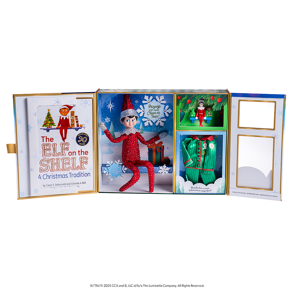 A open-faced view of the limited edition, collectable Swarovski® packaging of the 20th anniversary commemorative keepsake box with Swarovski® touches, featuring the posable Scout Elf® adorned in Swarovski® crystals, the artfully illustrated 20th anniversary edition storybook, limited-edition luxury satin long pajama set, limited-edition keepsake Scout Elf® ornament. 