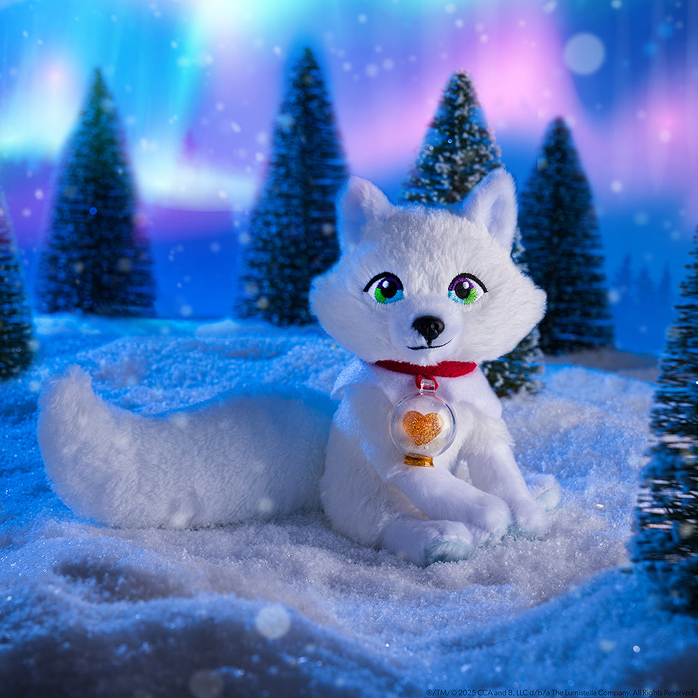 The Elf Pets® Arctic Fox plush in a wintery environment with an aurora sky, conifer trees and snow.