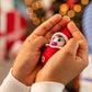 Frost Pips™ girl being held in a little girl's hands with a Christmas tree in the background