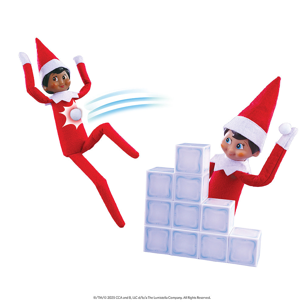 A pair of Scout Elves are having a snowball fight using props from the Polar Props™ The Official Elf Ideas Fun & Games Kit. One Scout Elf is posed taking cover and launching snowballs from behind an ice block wall, while another is getting tagged with a snowball in a fun illustration.