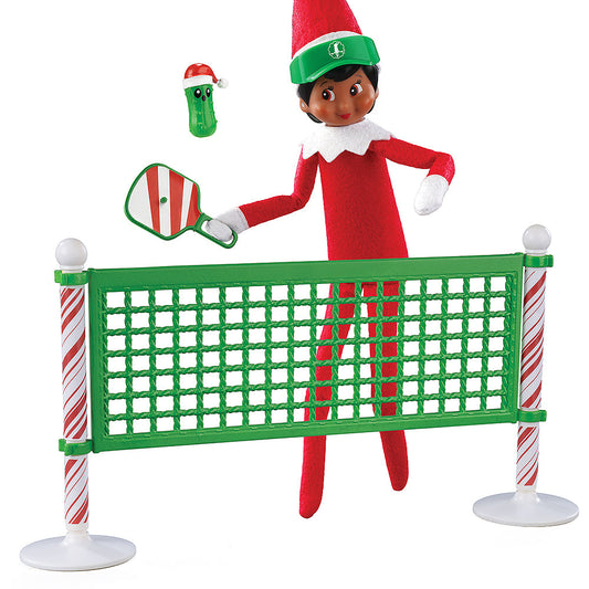 A girl Scout Elf playing pickleball with the Polar Props™ Pickleball Play Pack. She is taking a swing at the festive pickle at the net.
