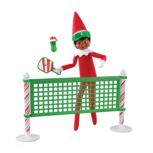 A girl Scout Elf playing pickleball with the Polar Props™ Pickleball Play Pack. She is taking a swing at the festive pickle at the net.