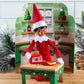 A Scout Elf® staged with the Polar Props™ 24-Day Ultimate Elf Ideas Kit items from Day 9, which is a kitchen backdrop, a kitchen table and a toaster, 2 slices of bread and a plate