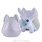 A tilted side-view of the front of packaging of the Noorah™ Snow Sculpture Surprise, which features Noorah's head as a plastic surprise container, pictured open with the cute reindeer character in white and light blue positioned inside the back piece of the container.