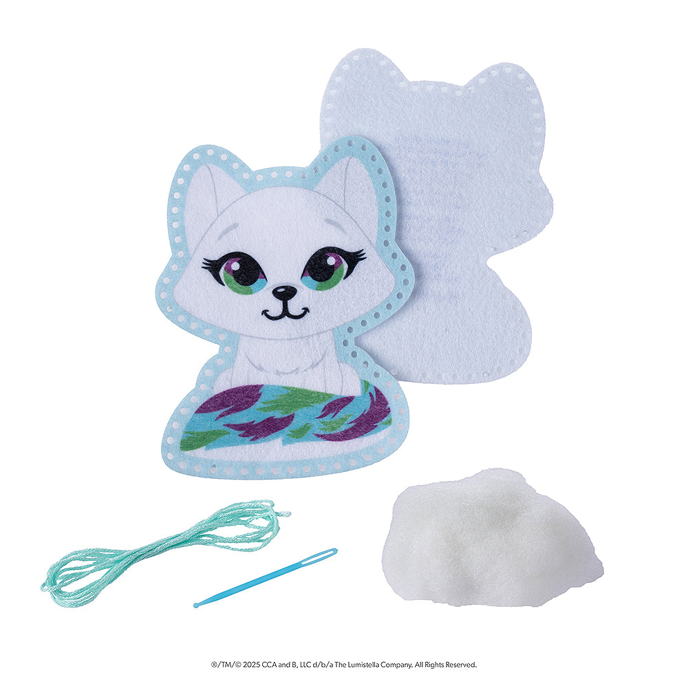 This image features the included items of the Noorah® Easy-Sew Ornament Kit. The included items are a front and back felt cutout of Noorah, which is perforated around the edges, a needle, some thread and cotton stuffing.