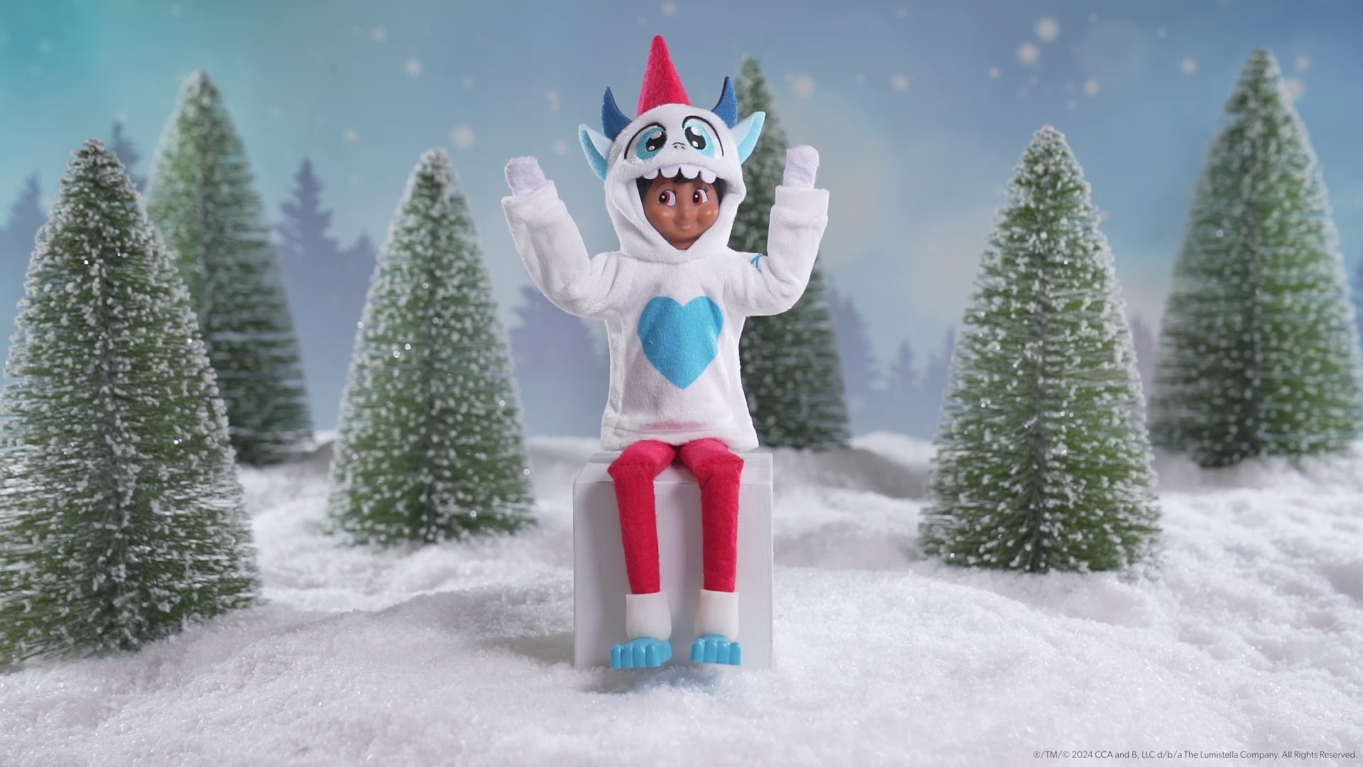 A Scout Elf® sitting in a snowy forest donning the Claus Couture Collection® Yeti Hoodie Set, spinning around in this product video to give customers a 360 degree view of the product