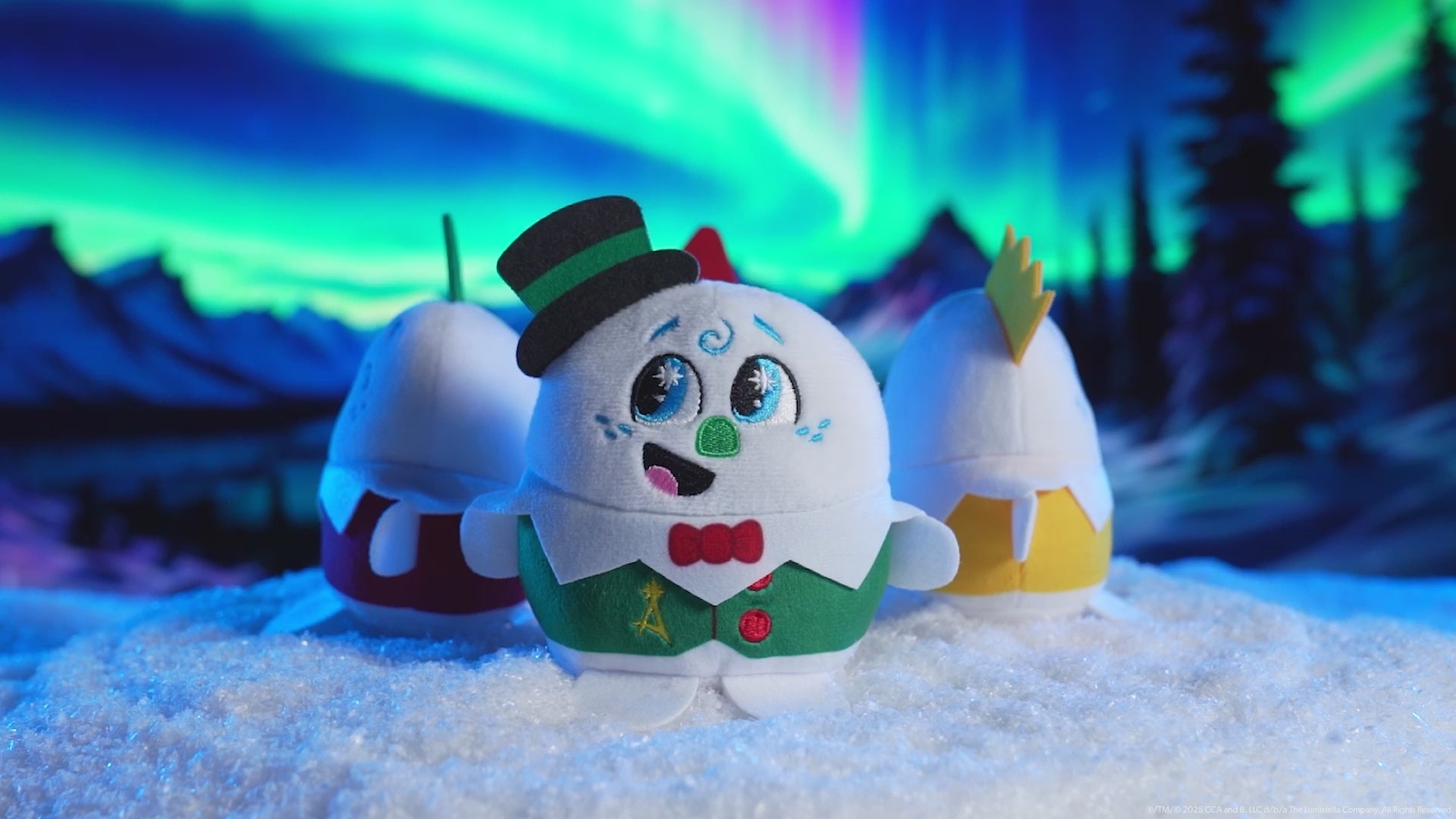 Product video showing all four playable plush celebration snowmen on a turntable in a snowy environment with the Northern Lights overhead. These pint-sized North Pole pals are stirring up a celebration for the 20th year of The Elf on the Shelf®! Collect all four and celebrate the season!