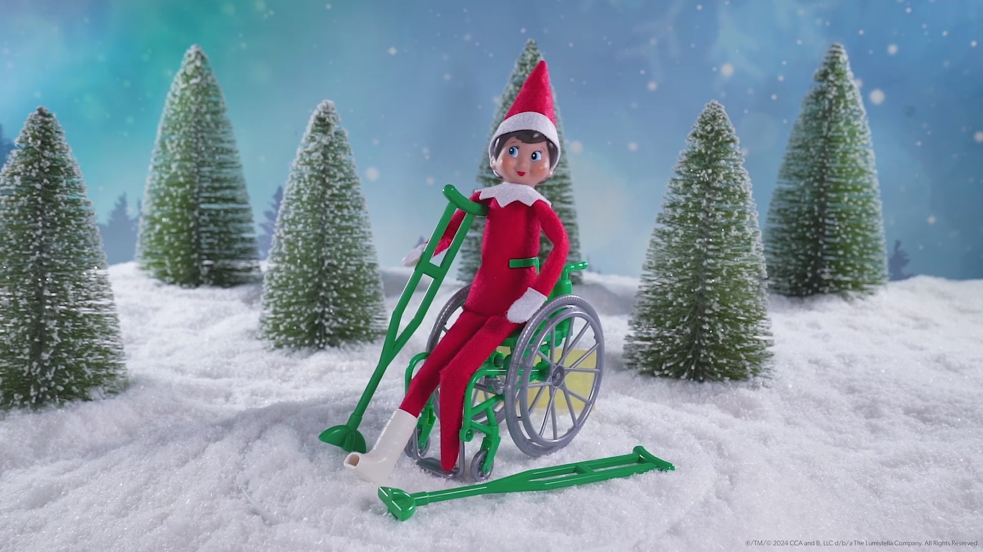 A Scout Elf® sitting in the wheelchair wearing the cast with crutches included in the Polar Props™ Elfcare Mobility Set, spinning around in this product video to give customers a 360 degree view of the product