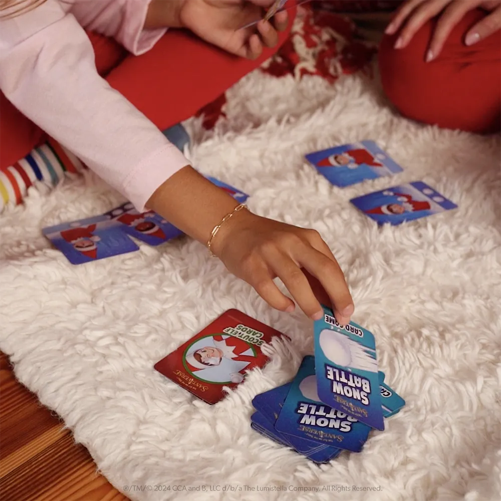 Girl picking up a Snow Battle card from a pile on the floor